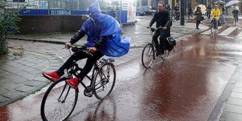 Gente en bicicleta bajo la lluvia