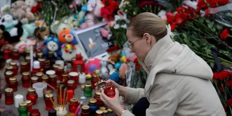Mujer encendiendo velas por el ataque en Moscú