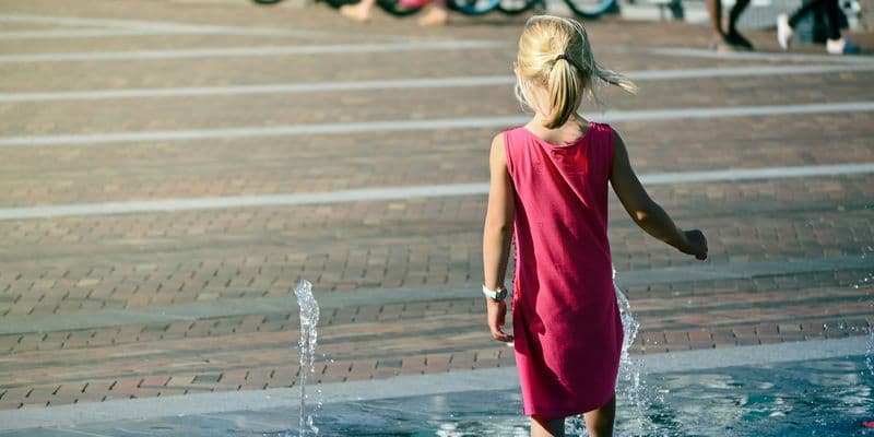 Niña jugando en una fuente de agua